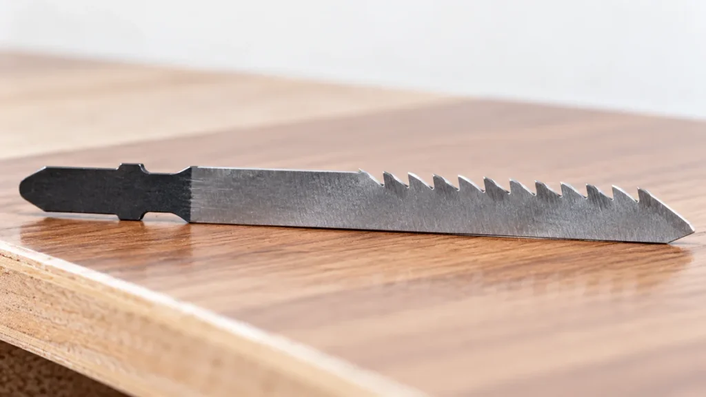 Reverse-cut jigsaw blade beside a finished wood veneer surface